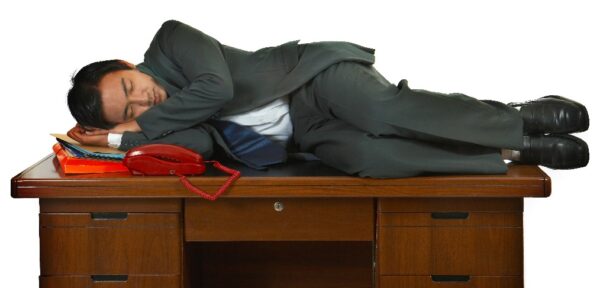 a man laying on his deck on his papers next to a red phone