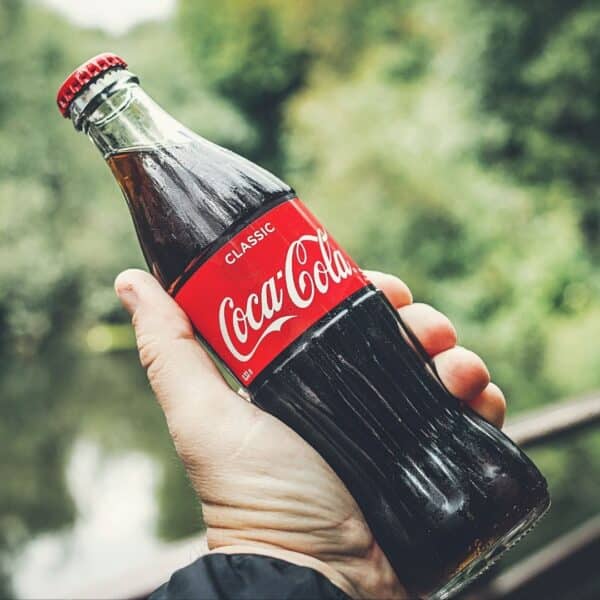 a hand holding up a coca cola bottle